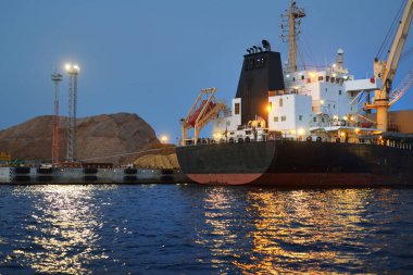 Riga Limanı, Letonya 'ya demir atmış büyük bir kargo gemisi, geceleri yakın plan. Yük taşımacılığı, küresel iletişim, lojistik, çevresel hasar teması