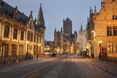 St. Michael köprüsü yakınlarındaki aydınlık cadde ve Gent şehrinin tarihi merkezindeki St. Bavo Katedrali. Gece manzarası. Seyahat rehberi, ulusal dönüm noktası, gezi teması. Belçika