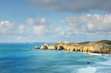 Pointe de Pen-Hir 'in kayalık sahili, uçurumlara yakın. Bulutlu mavi gökyüzü, masmavi su, fırtınalı dalgalar. Dramatik bulut manzarası. Crozon Yarımadası, Britanya, Fransa