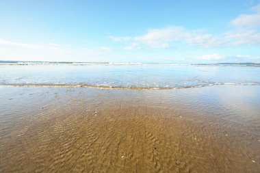 Douarnenez körfezinin kumlu sahilinden bir manzara. Açık mavi gökyüzü. Sudaki yansımalar. Dalgalar ve su sıçramaları. Brittany, Fransa. Seyahat yerleri, boş zaman etkinlik teması