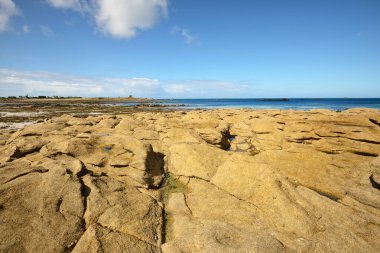 Güneşli bir günde, Lilia Körfezi 'nin Rocky kıyısında, Le Vierge deniz fenerinin yanında. Kadim taşlara yakın çekim. Plouguerneau, Finistre, Brittany, Fransa. Seyahat yerleri, ulusal dönüm noktaları.