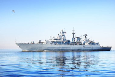 Durgun suda yüzen büyük gri modern savaş gemisi. Açık mavi gökyüzünde uçan martı. Baltık Denizi, Almanya