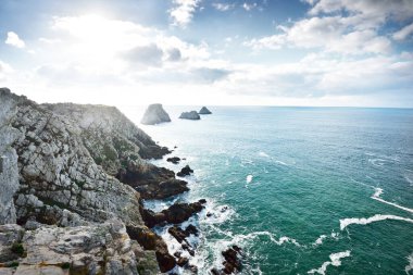 Pointe de Pen-Hir 'in kayalık sahili, uçurumlara yakın. Bulutlu mavi gökyüzü, masmavi su, fırtınalı dalgalar. Dramatik bulut manzarası. Crozon Yarımadası, Britanya, Fransa