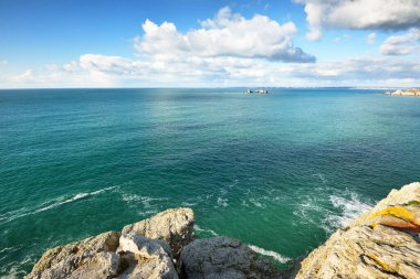 Pointe de Pen-Hir 'in kayalık sahili, uçurumlara yakın. Bulutlu mavi gökyüzü, masmavi su, fırtınalı dalgalar. Dramatik bulut manzarası. Crozon Yarımadası, Britanya, Fransa