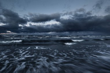 Kışın Baltık Denizi 'nin üzerindeki fırtına bulutları, uzun pozlama. Dramatik günbatımı gökyüzü, dalgalar ve su sıçramaları. Koyu deniz manzarası. Almanya