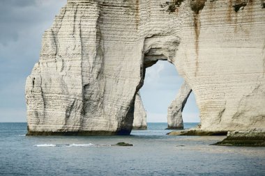 Etretat 'ın beyaz kayalıklarının manzarası panoramik alçak açılı. Dramatik gökyüzü, atmosferik manzara. Fransa, Normandiya 'da yaz tatili. Seyahat yeri, ulusal dönüm noktası, manzara, tarih.