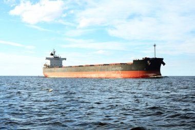 Büyük bir yük gemisi (kargo gemisi) Europoort 'tan açık denizlere açılır. Açık mavi gökyüzü ve sirrus bulutları. Rotterdam, Hollanda. Küresel iletişim, lojistik, endüstri teması