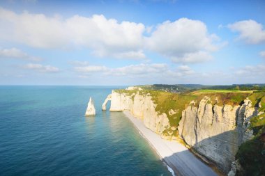Gün batımında Etretat beyaz uçurumlarının manzaralı panoramik görüntüsü. Dramatik gökyüzü, gök mavisi su. Fransa, Normandiya 'da yaz tatili. Seyahat yerleri, ulusal dönüm noktaları, geziler, tarih.