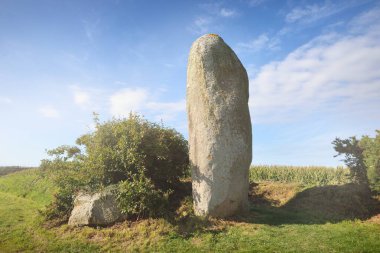 Ploguerneau, Brittany, Fransa 'da büyük bir Menhir taşı. Açık mavi gökyüzünün altında yeşil bir çayır. Kültür ve din, ulusal dönüm noktası, seyahat yerleri, gezi teması