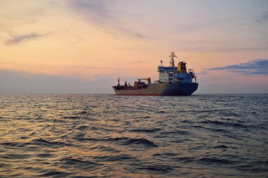 Büyük gri bir tanker gün batımında Europort 'tan denize açılacak. Renkli akşam bulutları. Rotterdam, Hollanda. Lojistik, ticaret, küresel iletişim teması