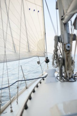 Güneşli bir yaz gününde beyaz bir yat denize açılıyor. Güverteden pruva ve yelkenlere kadar yakın çekim. Dalgalar ve su sıçramaları. Açık mavi gökyüzü. Baltık Denizi, İsveç
