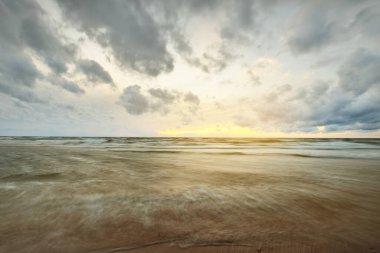 Danimarka 'da fırtınadan sonra, Baltık Denizi' nin üzerinde destansı renkli, parlayan günbatımı bulutları. Kumlu sahilden bir manzara. Dramatik deniz manzarası. Kavramsal görüntü, uzun pozlama. Resim gibi bir manzara.