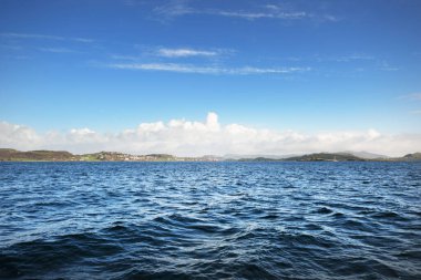 Yelkenliden Kuzey Denizi manzarası. Açık mavi gökyüzü suya yansıyor. Arka planda fiyortlar var. Rogaland bölgesi, Norveç. Spor, eğlence, eğlence aktivitesi, çevre koruma