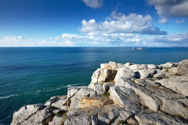 Pointe de Pen-Hir 'in kayalık sahili, uçurumlara yakın. Bulutlu mavi gökyüzü, masmavi su, fırtınalı dalgalar. Dramatik bulut manzarası. Crozon Yarımadası, Britanya, Fransa