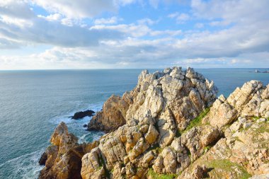 Pointe de Pen-Hir 'in kayalık sahili, uçurumlara yakın. Bulutlu mavi gökyüzü, masmavi su, fırtınalı dalgalar. Dramatik bulut manzarası. Crozon Yarımadası, Britanya, Fransa