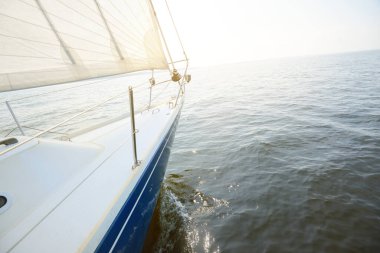 Güneşli bir yaz gününde beyaz bir yat denize açılıyor. Güverteden pruvaya, direğe ve yelkenlere kadar yukarıdan aşağı görüş. Dalgalar ve su sıçramaları. Açık mavi gökyüzü. Finlandiya Körfezi