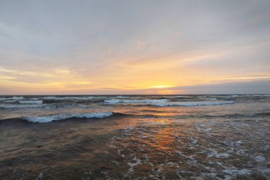Gün batımında Anholt Adası 'nın kumsal kıyısında. Dalgalar ve su sıçramaları. Renkli bulutlu bir manzara. Çevre koruma, eko turizm teması. Kattegat, Danimarka
