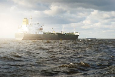 Büyük bir kargo gemisi dramatik fırtınalı gökyüzünün altında açık denizde yelken açıyor. Destansı deniz manzarası. Nakliye, küresel iletişim, teslimat, yakıt ve güç üretimi, endüstri, lojistik