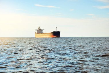 Büyük bir yük gemisi (kargo gemisi) Europoort 'tan açık denizlere açılır. Açık mavi gökyüzü ve sirrus bulutları. Rotterdam, Hollanda. Küresel iletişim, lojistik, endüstri teması