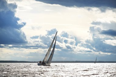Yelkenli yat yarışı. Modern yelkenli dalgalar arasında yarışıyor. Fırtınadan önce dramatik gökyüzü. Muazzam bulut manzarası. Kuzey Almanya, Kiel