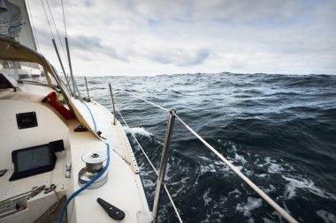Bulutlu bir günde Kuzey Denizi 'nde yelken açan beyaz bir yat. Karanlık fırtına gökyüzü suya yansıyor. Rogaland bölgesi, Norveç. Spor, eğlence, eğlence etkinlik teması