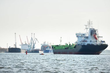 Büyük siyah tanker (kargo gemisi) limana yaklaşıyor, yakın plan. Riga Körfezi, Baltık Denizi, Letonya. Yük taşımacılığı, küresel iletişim, lojistik, çevresel hasar teması
