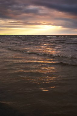 Dramatik günbatımı bulutları altında fırtınalı Baltık Denizi. Kumlu sahilden bir manzara. Riga Körfezi, Letonya. Destansı deniz manzarası. Karanlık sonbahar sahnesi. Meteoroloji, ekoloji, çevre koruma, iklim değişikliği