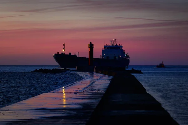 日没時に灯台近くを航行する大型貨物船 カラフルな雲の風景 リガ湾 バルト海 ラトビア 国際通信 物流をテーマに — ストック写真