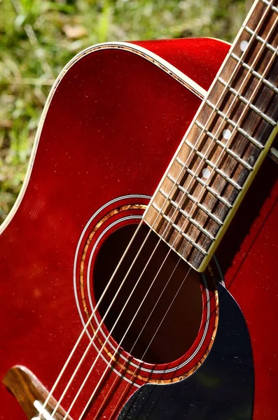 经典的红色声吉他特写 背景为绿茵的春林 音乐和乐器 业余爱好 休闲活动 度假主题 — 图库照片
