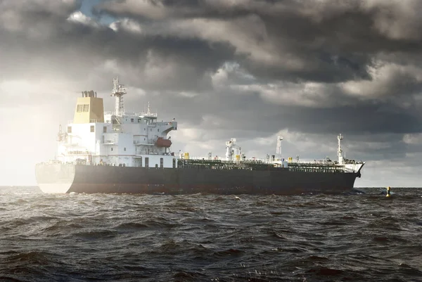 Büyük bir kargo gemisi dramatik fırtınalı gökyüzünün altında açık denizde yelken açıyor. Destansı deniz manzarası. Nakliye, küresel iletişim, teslimat, yakıt ve güç üretimi, endüstri, lojistik