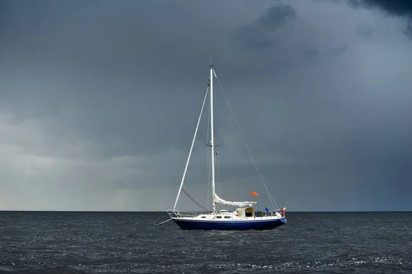 ブルースループは 雷雨の後 暗い空の下で英国の海岸沖に固定されたヨットを操縦しました 荒天時に出航する 劇的な海景 雲の中から太陽の光 — ストック写真