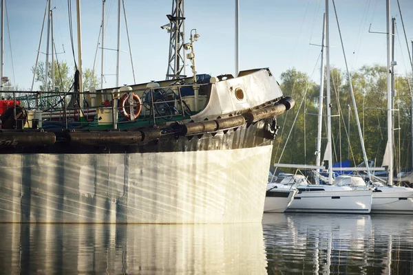 Small ship (fishing boat) moored to a pier in a yacht marina, close-up. Daugava river, Riga, Latvia. Transportation, industry, traditional craft concepts