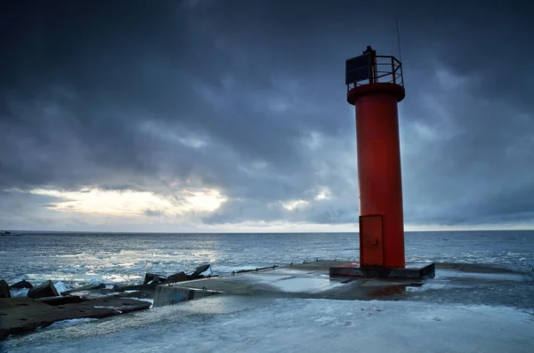 太陽電池で赤い灯台への空の遊歩道 クローズアップ 背景に凍結バルト海 暗い嵐の雲 代替エネルギー 気候変動 地球温暖化の概念 長時間露光 — ストック写真