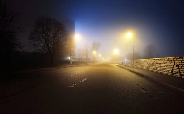 夜雾中一条空旷的灯火通明的高速公路和关闭的商店 道路标志着特写 黑暗的城市景象 城市景观 拉脱维亚里加 危险驾驶 概念形象 — 图库照片