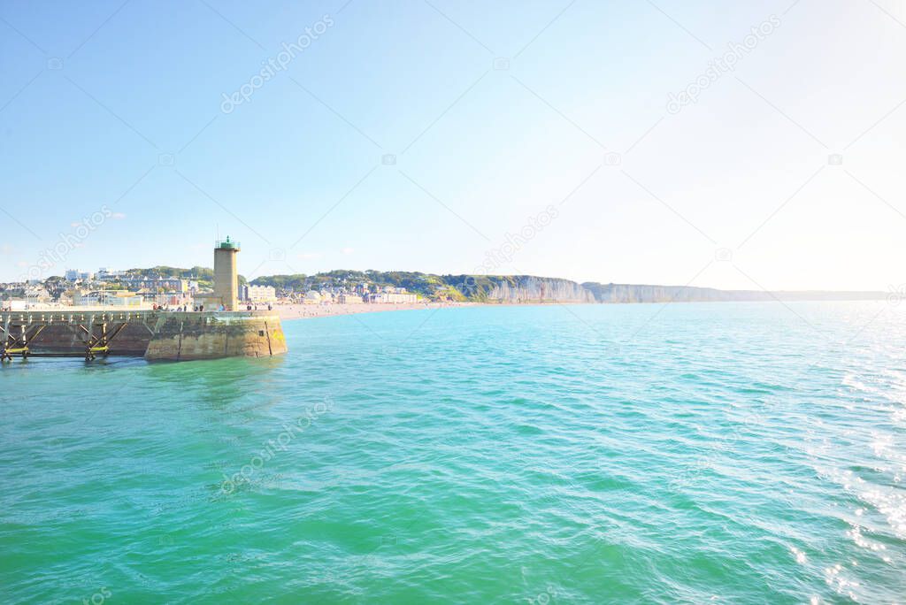 A beach and a way to the lighthouse near white cliffs and English Channel on a clear day. Fcamp, Normandy, France. Blue sky, azure water. Nature, history, past, national landmark, sightseeing, travel.
