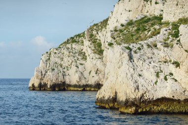 Kayalık kıyılar (uçurumlar) yakın çekim, yelkenli teknenin manzarası. Frioul takımadaları, Akdeniz, Marsilya Körfezi, Fransa. Seyahat yerleri, ulusal dönüm noktaları, geziler, tatiller.