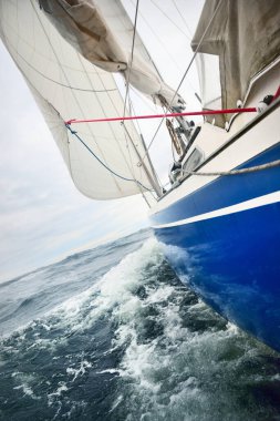 Yağmurlu bir günde, fırtınalı bir havada yat gezintisi. Güverteden pruvaya, direğe ve yelkenlere yakın görüntü. Dramatik fırtınalı gökyüzü, kara bulutlar. Dalgalar ve su sıçramaları. Kötü hava. Baltık Denizi, İsveç