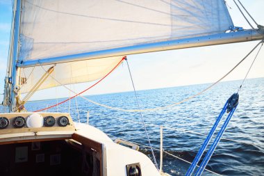 Güneşli bir günde açık denizde beyaz yelkenli, güverteden pruvaya yakın görüntü, direk ve yelkenli. Tek başına 10 metrelik bir yata biniyor. İngiltere, İngiltere. Spor, yarış, eğlence.