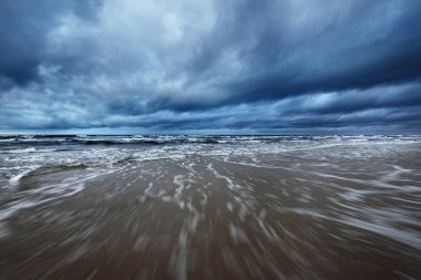 Kışın Kuzey Denizi 'nin yukarısında fırtına bulutları, uzun pozlama. Dramatik gökyüzü, dalgalar ve su sıçramaları. Koyu deniz manzarası. Hollanda