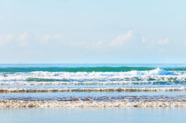 Douarnenez körfezinin kumlu sahilinden bir manzara. Açık mavi gökyüzü. Sudaki yansımalar. Dalgalar ve su sıçramaları. Brittany, Fransa. Seyahat yerleri, boş zaman etkinlik teması