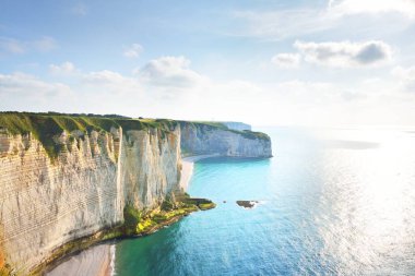 Gün batımında Etretat beyaz uçurumlarının manzaralı panoramik görüntüsü. Dramatik gökyüzü, gök mavisi su. Fransa, Normandiya 'da yaz tatili. Seyahat yerleri, ulusal dönüm noktaları, geziler, tarih.