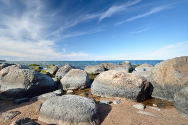 Baltık Denizi 'nin kayalık kıyıları açık mavi gökyüzünün altında, sirrus bulutlarıyla. Kadim taşlara yakın çekim. Bahar. Kasmu doğa rezervi, Estonya. Ekoloji, çevre koruma, eko turizm kavramları
