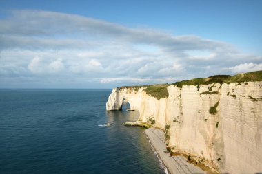 Gün batımında Etretat beyaz uçurumlarının manzaralı panoramik görüntüsü. Dramatik gökyüzü, gök mavisi su. Fransa, Normandiya 'da yaz tatili. Seyahat yerleri, ulusal dönüm noktaları, geziler, tarih.