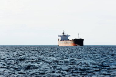 Büyük bir yük gemisi (kargo gemisi) Europoort 'tan açık denizlere açılır. Açık mavi gökyüzü ve sirrus bulutları. Rotterdam, Hollanda. Küresel iletişim, lojistik, endüstri teması