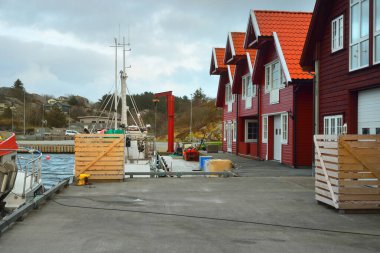 Sürat tekneleri, yelkenliler ve balıkçı tekneleri Norveç 'in Rogaland bölgesindeki küçük bir köydeki bir rıhtıma demirlediler. Geleneksel mimari. Dramatik akşam gökyüzü. Seyahat yerleri, tatiller, boş zaman aktiviteleri
