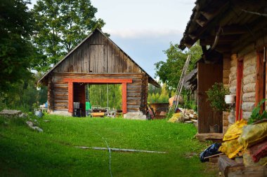 Yeşil huş ağacı ormanında eski bir kır evi (ahşap kulübe veya kulübe). Pastoral manzara. Arka planda bahçe ekipmanları var. Eko turizm, eğlence teması. Setomaa, Estonya