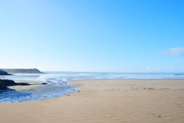 Douarnenez körfezinin kumlu sahilinden bir manzara. Açık mavi gökyüzü. Sudaki yansımalar. Dalgalar ve su sıçramaları. Brittany, Fransa. Seyahat yerleri, boş zaman etkinlik teması