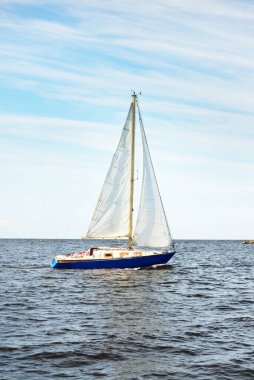 Açık bir günde deniz fenerinin yanında yelken açan küçük bir yat. Riga Körfezi, Baltık Denizi, Letonya. Gezi, spor, eğlence, boş zaman aktiviteleri.