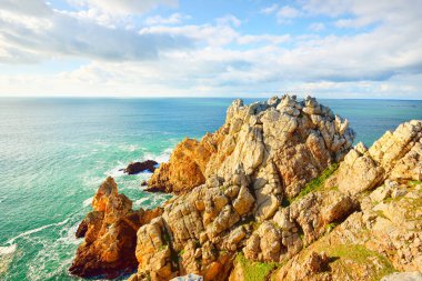 Pointe de Pen-Hir 'in kayalık sahili, uçurumlara yakın. Bulutlu mavi gökyüzü, masmavi su, fırtınalı dalgalar. Dramatik bulut manzarası. Crozon Yarımadası, Britanya, Fransa