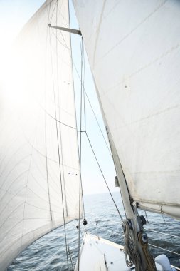 Güneşli bir yaz gününde beyaz bir yat denize açılıyor. Güverteden pruva ve yelkenlere kadar yukarıdan aşağıya doğru. Dalgalar ve su sıçramaları. Açık mavi gökyüzü. Baltık Denizi, İsveç
